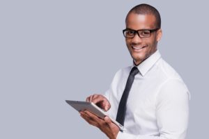 photo of a man using computer tablet while smiling at the camera